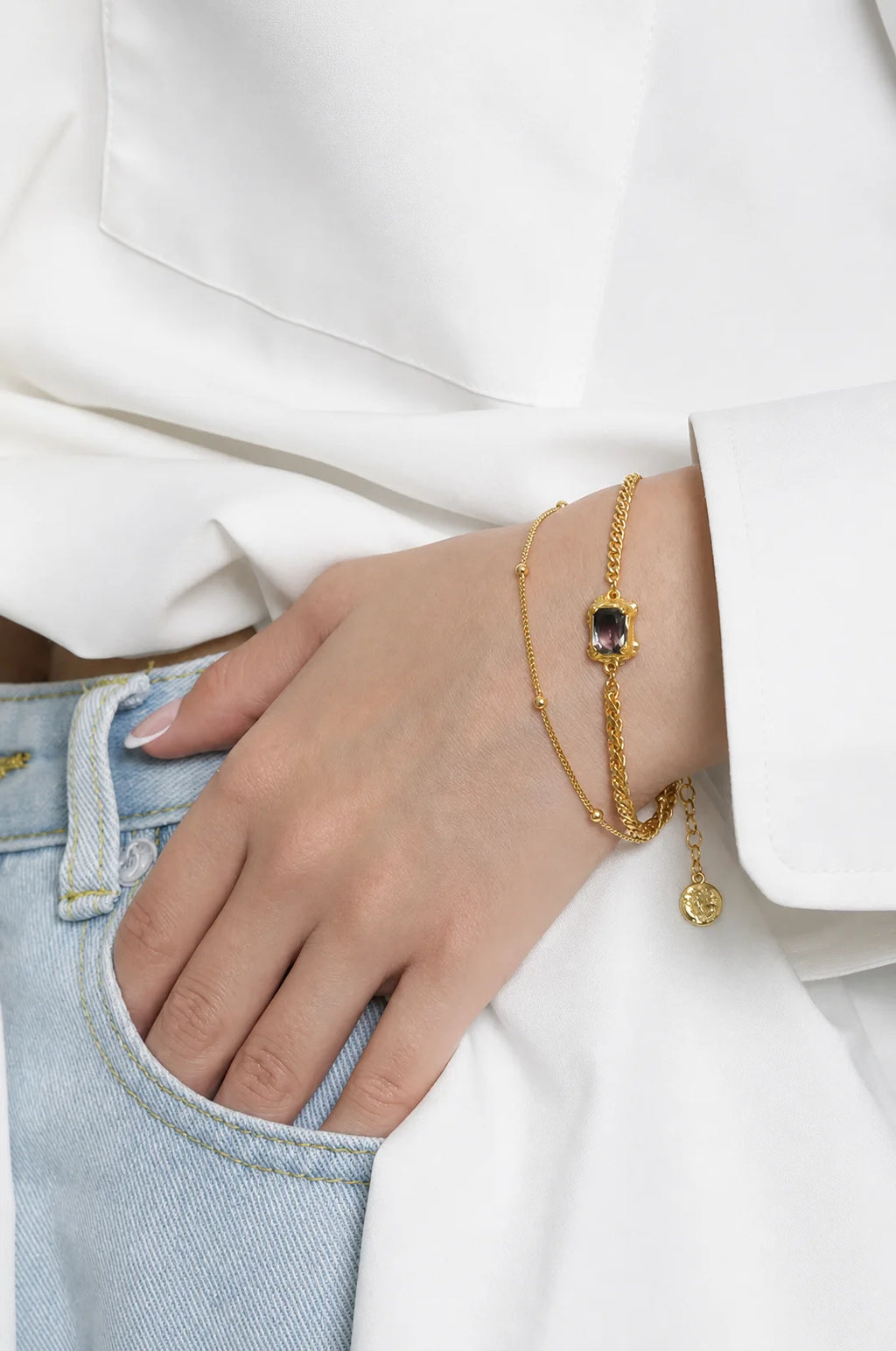 Frequency Paris-Ibiza Alchemy Chain Bracelet in gold worn with white blazer and blue jeans, luxury everyday styling