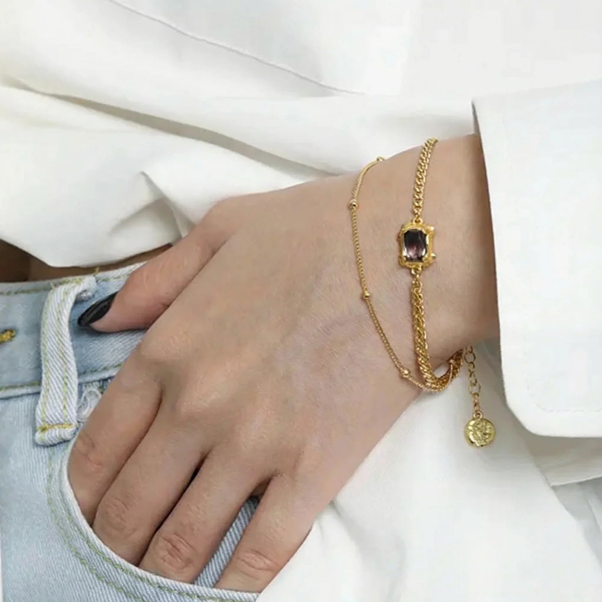 Frequency Paris-Ibiza Alchemy Chain Bracelet in gold worn with white blazer and blue jeans, luxury everyday styling