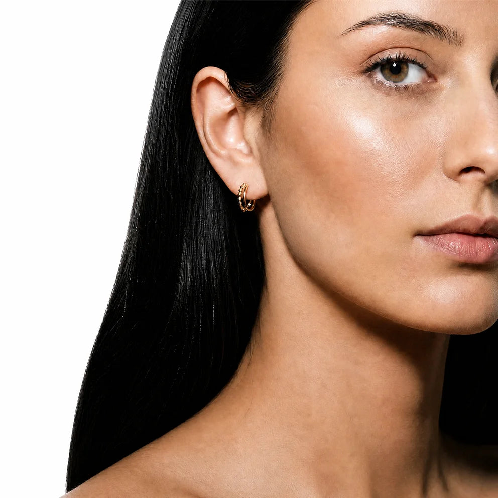 Model wearing Frequency Paris-Ibiza Divine Feminine Gold Hoop Earrings. Two-hoop illusion design in 18K gold-plated sterling silver, delicate, eye-catching, and versatile for everyday or special occasions.