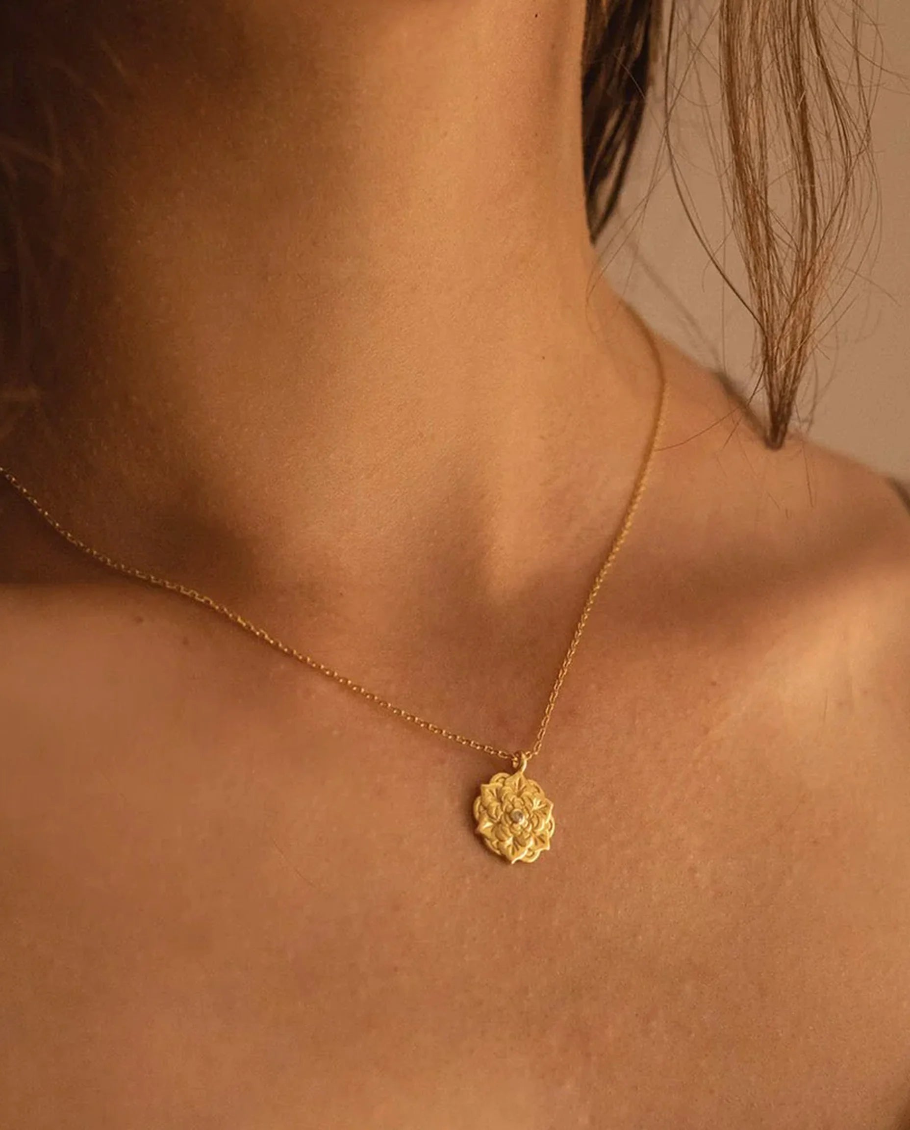 Empowerment Gold Pendant Necklace on model’s neck — gold chain with floral pendant and central crystal. Frequency Paris-Ibiza