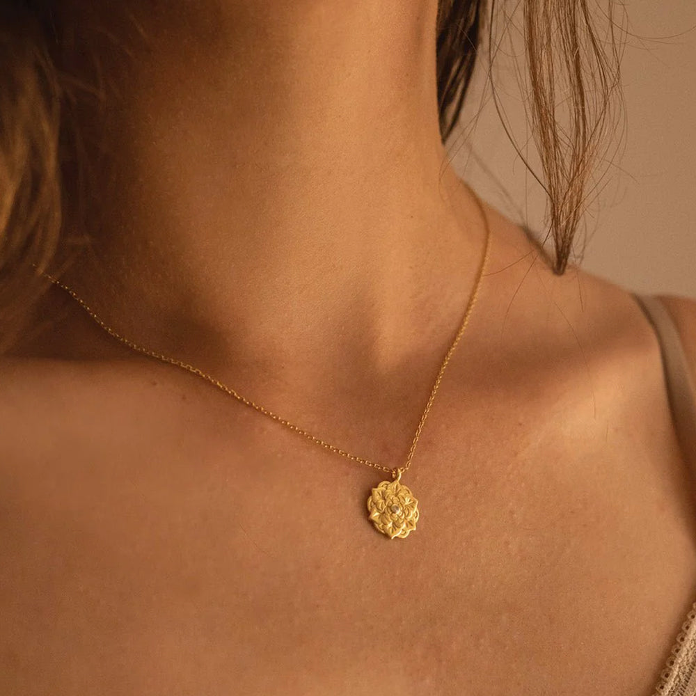 Empowerment Gold Pendant Necklace on model’s neck — gold chain with floral pendant and central crystal. Frequency Paris-Ibiza