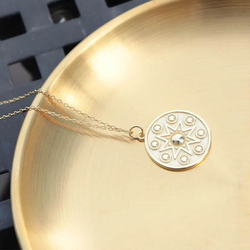 Manifest Gold Pendant Necklace by Frequency Paris Ibiza — softly resting on a gold bowl, reflecting light and intention in every polished detail.