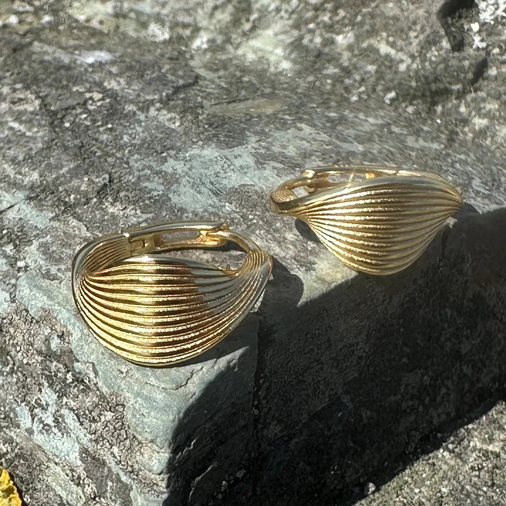 Frequency Paris-Ibiza 18K gold-plated Eternal Wave Hoop Earrings on organic rocks, highlighting wave ridged sculptural detail