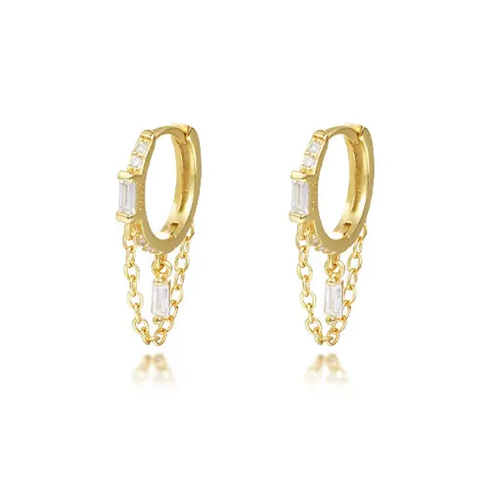 Close-up of Frequency Paris-Ibiza Infinity Huggie Earrings in 18k gold-plated sterling silver with clear zircon crystals on a white background.