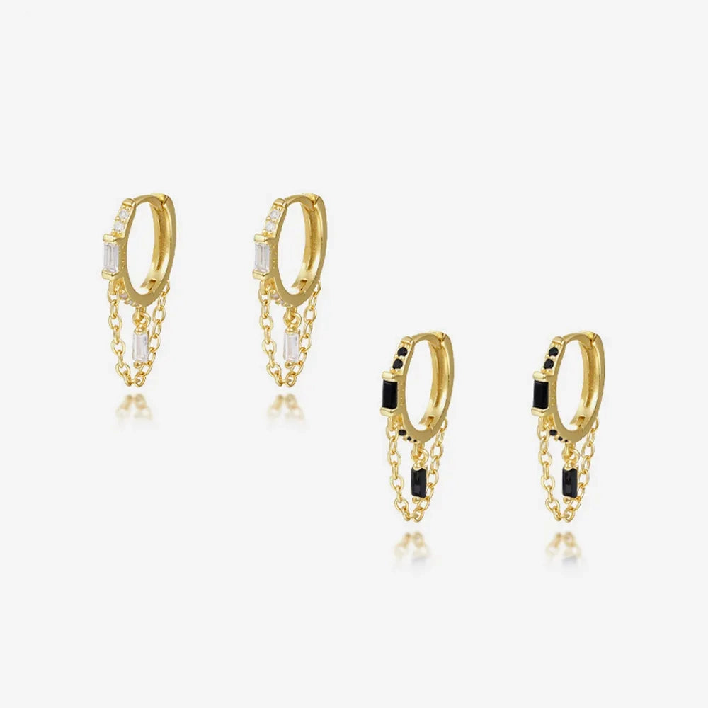 Frequency Paris-Ibiza Infinity Huggie Earrings displayed in both clear and black zircon crystal options, featuring 18k gold-plated sterling silver huggies with chain hoop detail.