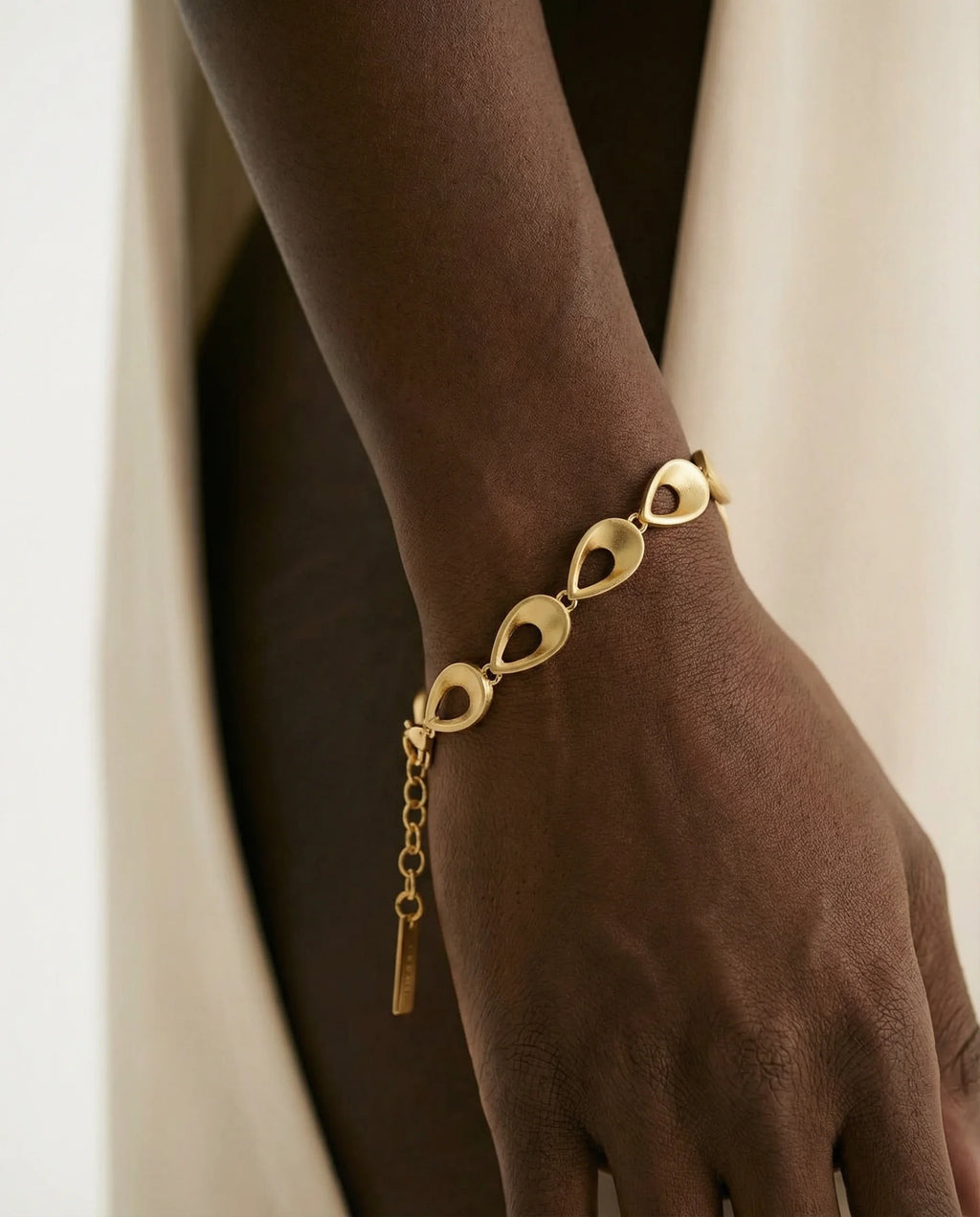 Frequency Paris Ibiza Light Codes Bracelet. 18k Gold plating on Premium Sterling Silver, styled with a contemporary
cream evening dress.