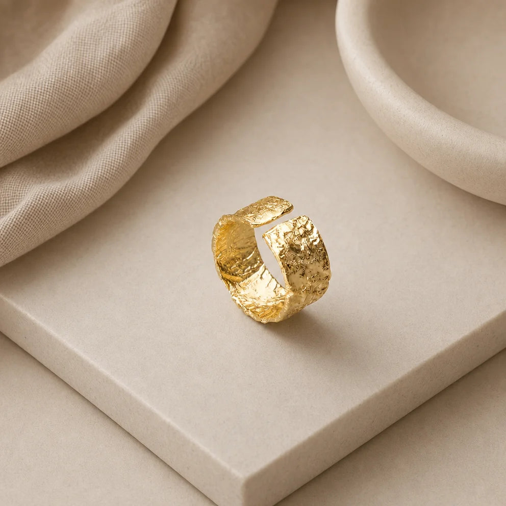 Gaia Ring by Frequency Paris-Ibiza displayed on a bed of crystals, highlighting its adjustable closing and organic hammered texture. The craftsmanship of the 18k gold-plated sterling silver ring exudes both beauty and quality.