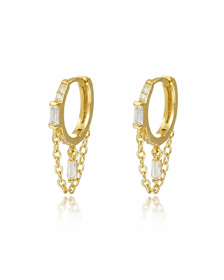Close-up of Frequency Paris-Ibiza Infinity Huggie Earrings in 18k gold-plated sterling silver with clear zircon crystals on a white background.