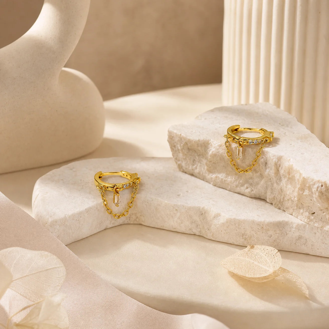 Close-up of Frequency Paris-Ibiza Infinity Huggie Earrings with clear zircon crystals, detailed crystal huggies, center drop crystal, and delicate chain hoop design in 18k gold-plated sterling silver.