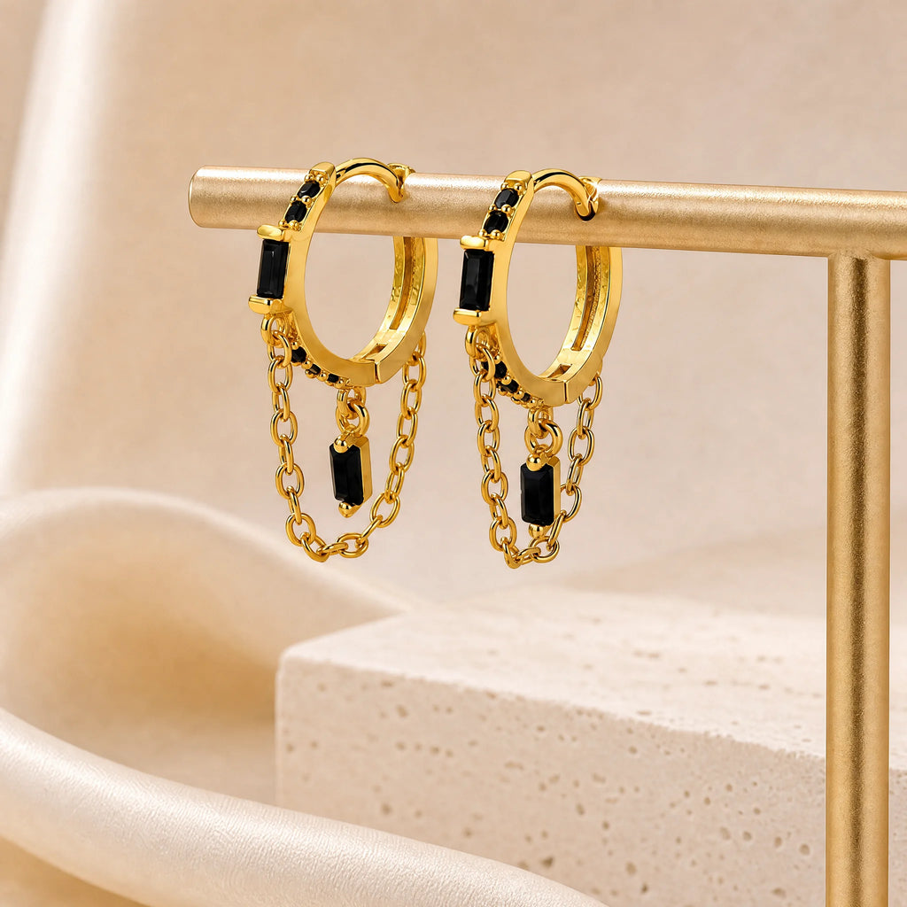 Close-up of Frequency Paris-Ibiza Infinity Huggie Earrings featuring black zircon crystals, highlighting the craftsmanship, chain hoop design, and 18k gold-plated sterling silver finish.