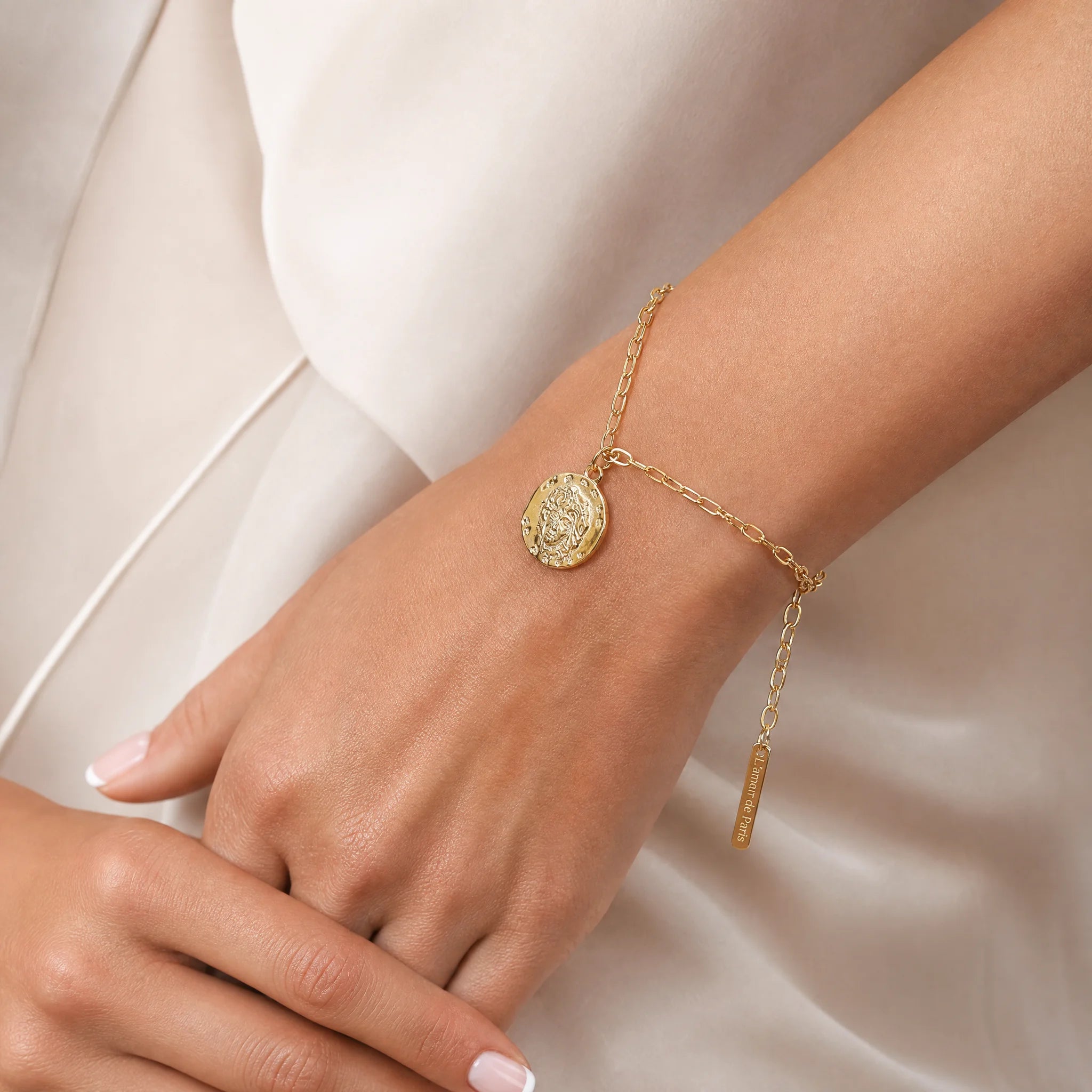 Frequency Paris-Ibiza L'Amour Gold Chain Bracelet on wrist with close-up of coin charm featuring face and L'Amour de Paris text
