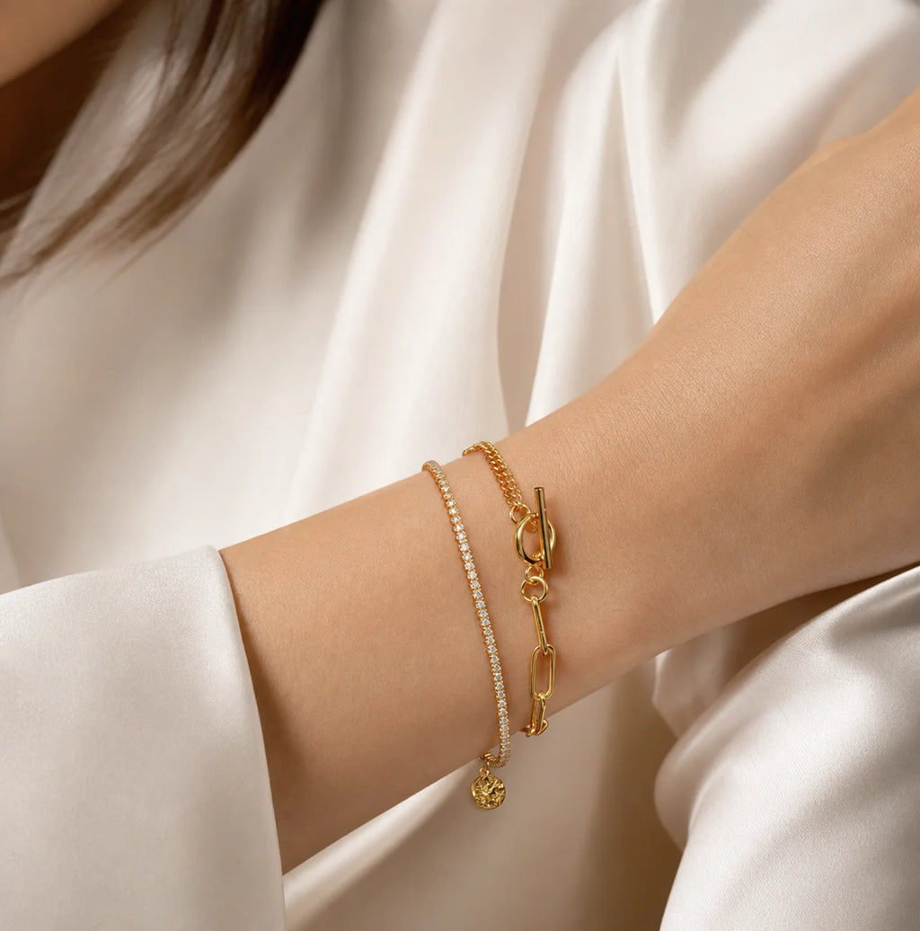Close-up of Frequency Paris-Ibiza Life Force gold bracelet worn with a smart blazer, highlighting double chains and zircon crystal strand.