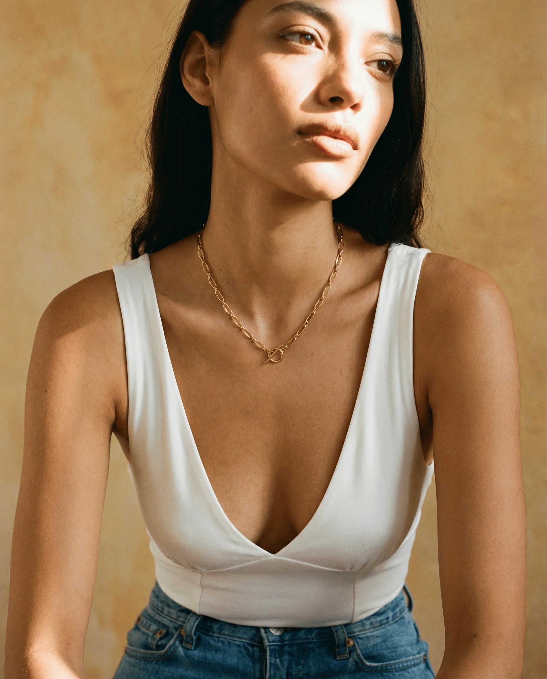 The perfect gift for her - The Burning Desire Necklace. Pictured here in Gold, styled with a white bodice and blue jeans. Shop now at Frequency Paris-Ibiza.