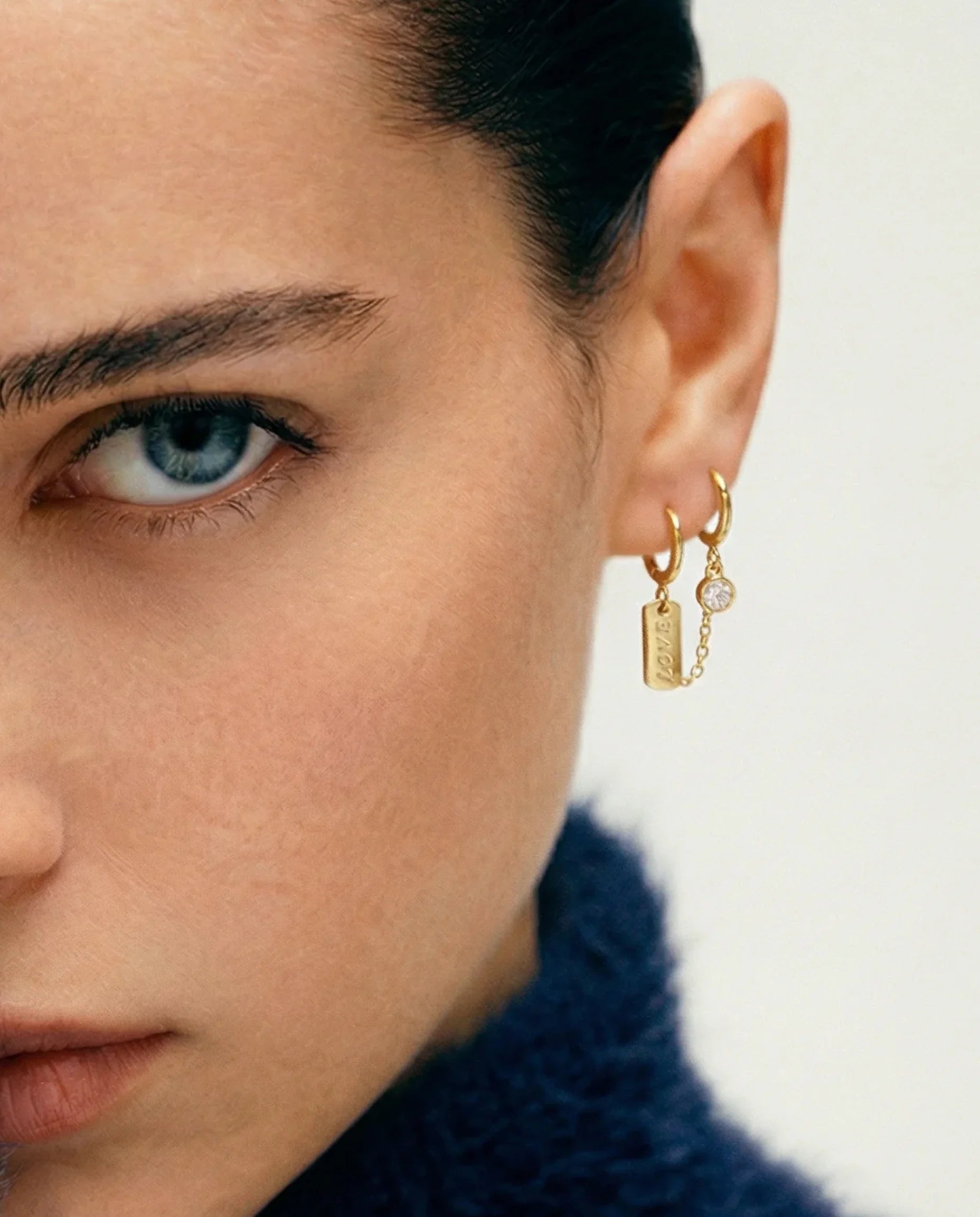 Frequency Paris-Ibiza gold Self Love Huggie Chain Earrings worn. Crystal gemstone is the focal point and ‘love’ tag sits elegantly on the second huggie.