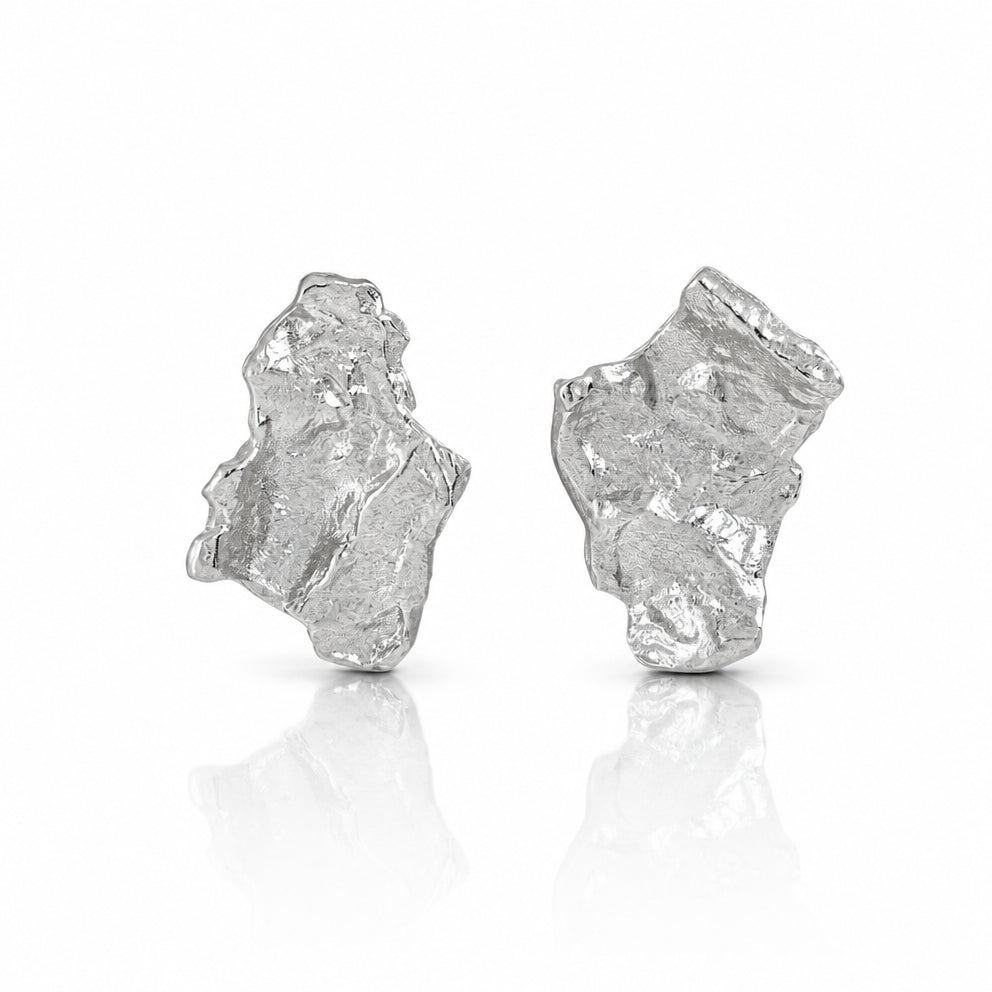Close-up of rhodium-plated sterling silver Grounding earrings with handcrafted hammered design. Organic texture in sleek silver, by Frequency Paris-Ibiza.