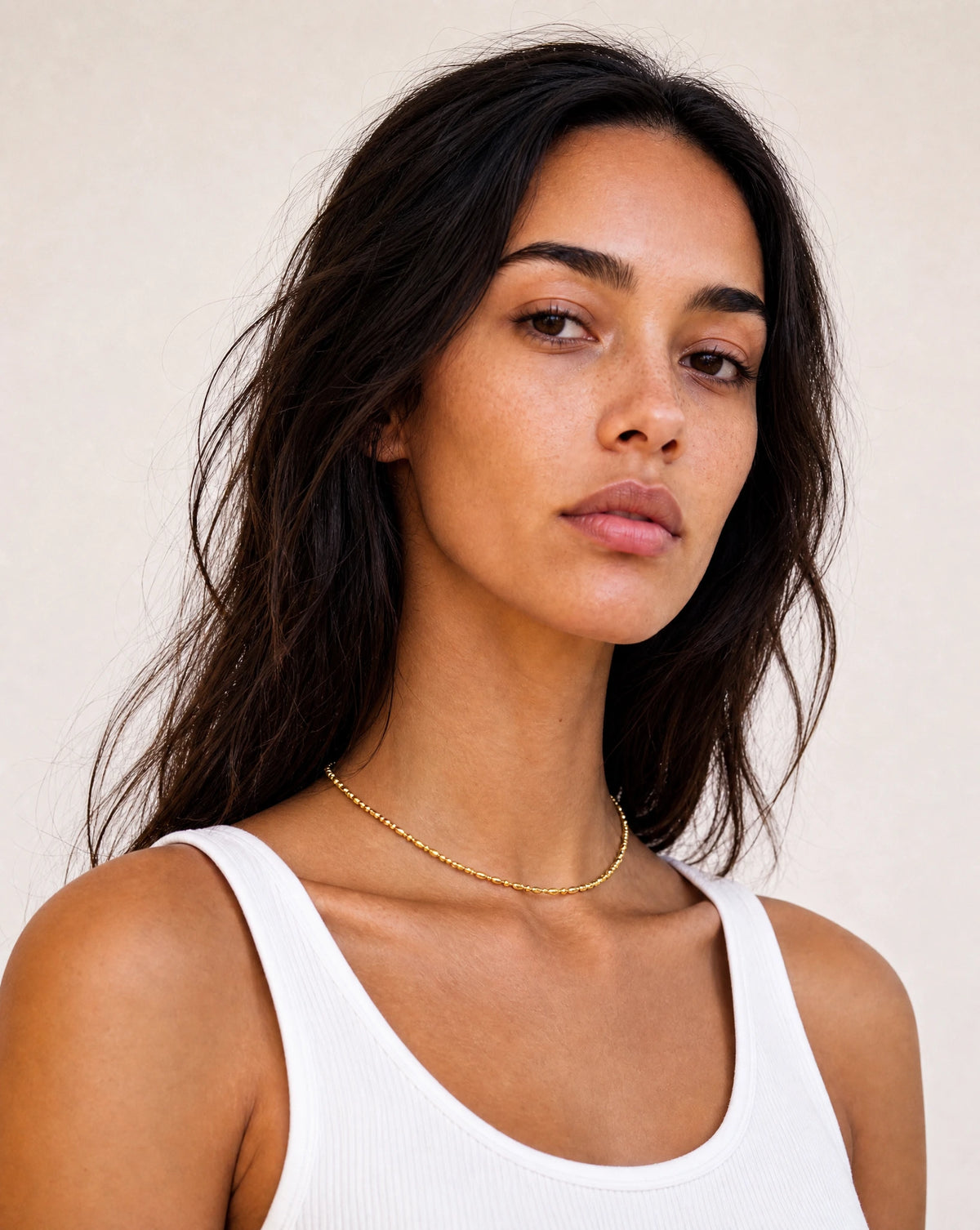 A model in a clean white vest wearing the Eclipse Gold Beaded Choker by Frequency Paris-Ibiza. The choker adds elegant polish to even a simple T-shirt. It’s the perfect gift for her, and the best layering piece to have in your jewellery box.
