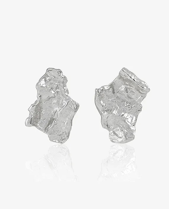 Close-up of rhodium-plated sterling silver Grounding earrings with handcrafted hammered design. Organic texture in sleek silver, by Frequency Paris-Ibiza.