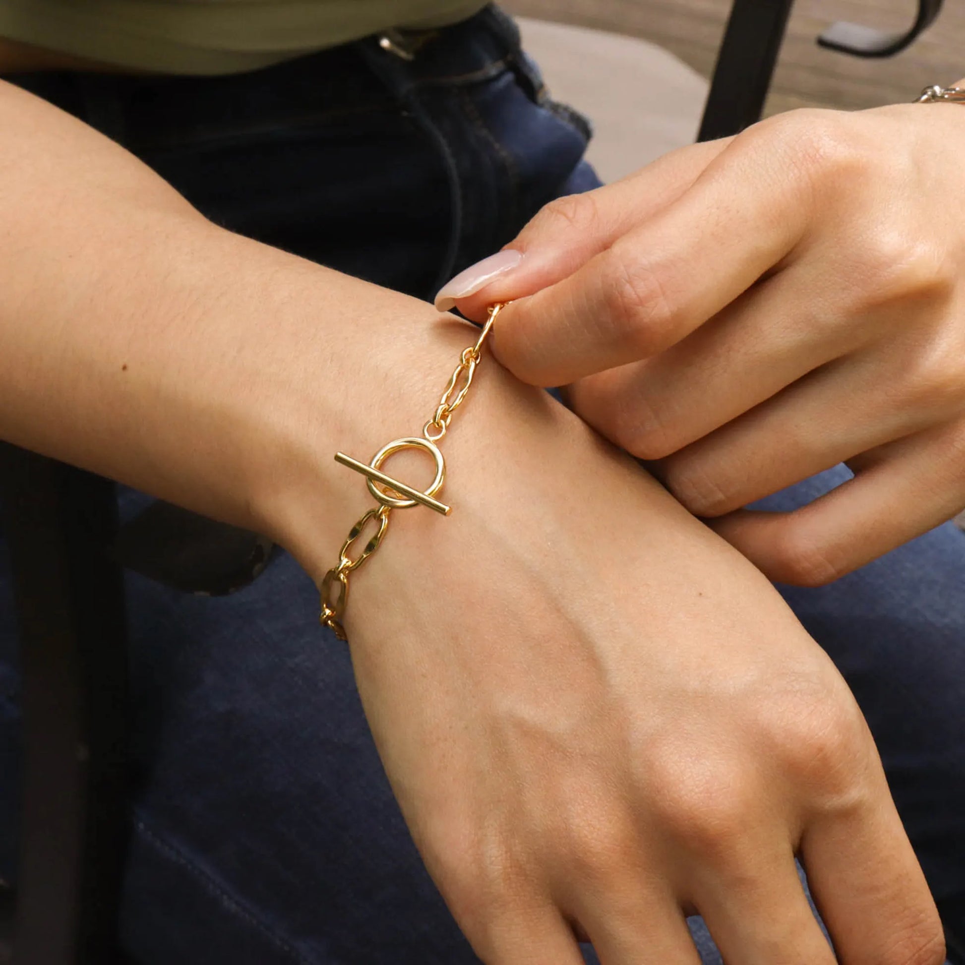 Model wearing the Frequency Paris-Ibiza Burning Desire gold T-bar bracelet showing the chain and T-bar fastening detail