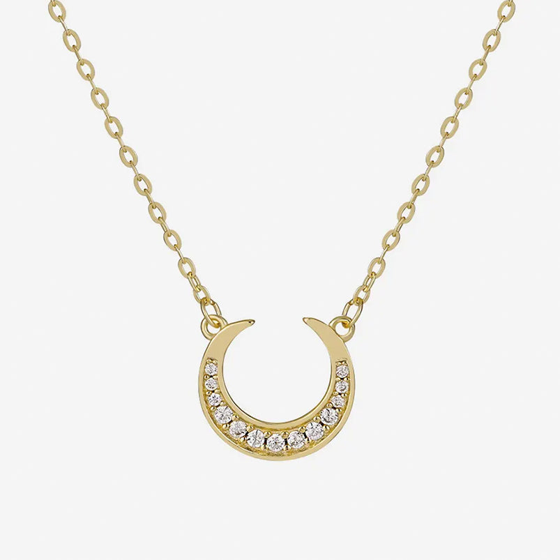 Dreamscape Gold Pendant Necklace by Frequency Paris-Ibiza — celestial crescent moon pendant with sparkling zircon crystals on white background, showing intricate details.