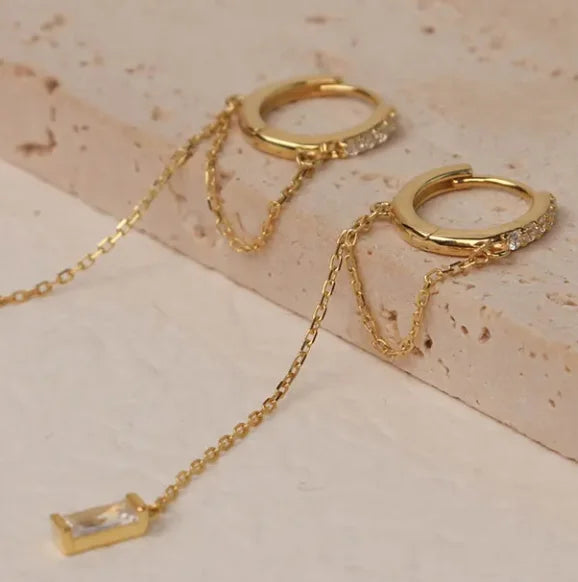 Close-up of Frequency Paris–Ibiza Infinity Chain Earrings in 18K gold, highlighting craftsmanship, zircon crystal detailing, and fine chain tassels.