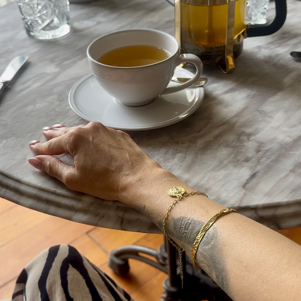 Frequency Paris-Ibiza L'Amour Gold Chain Bracelet styled on wrist with So Hum bracelet at afternoon tea