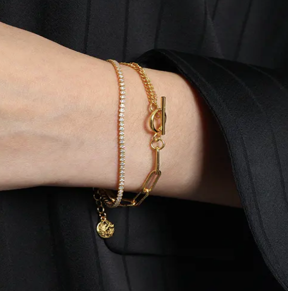 Close-up of Frequency Paris-Ibiza Life Force gold bracelet worn with a smart blazer, highlighting double chains and zircon crystal strand.