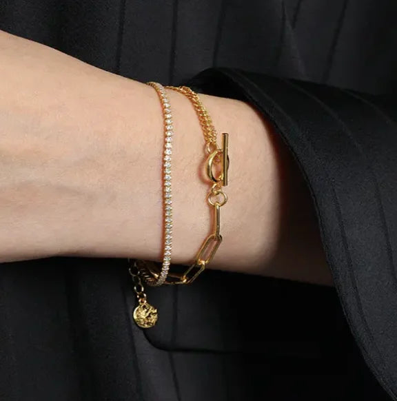 Close-up of Frequency Paris-Ibiza Life Force gold bracelet worn with a smart blazer, highlighting double chains and zircon crystal strand.