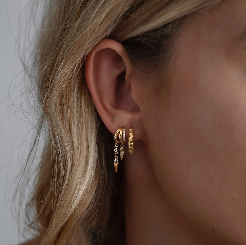 Model wearing the Frequency Paris–Ibiza Modern Goddess Drop Earrings showing the triple-piercing illusion with delicate spike drops and zircon crystal accents. 