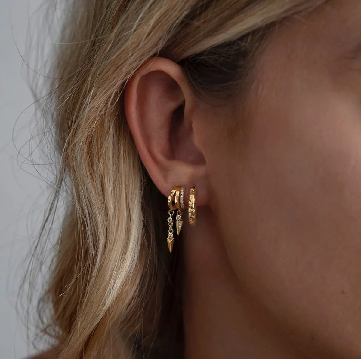 Model wearing the Frequency Paris–Ibiza Modern Goddess Drop Earrings showing the triple-piercing illusion with delicate spike drops and zircon crystal accents. 