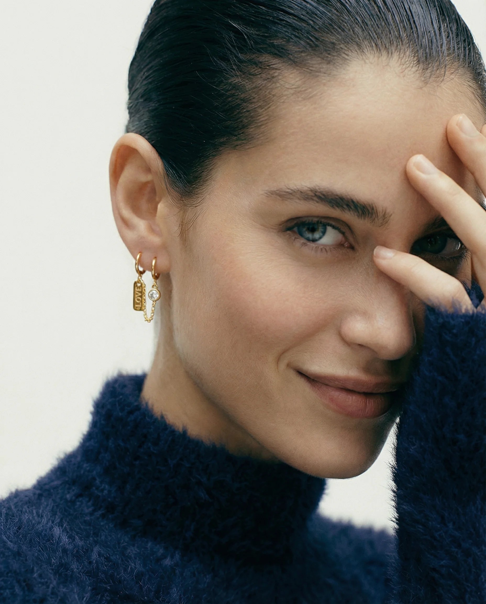 Model wearing the Self Love Huggie Chain Earring in gold by Frequency Paris-Ibiza – 18k gold-plated sterling silver huggies linked by a chain for double piercings