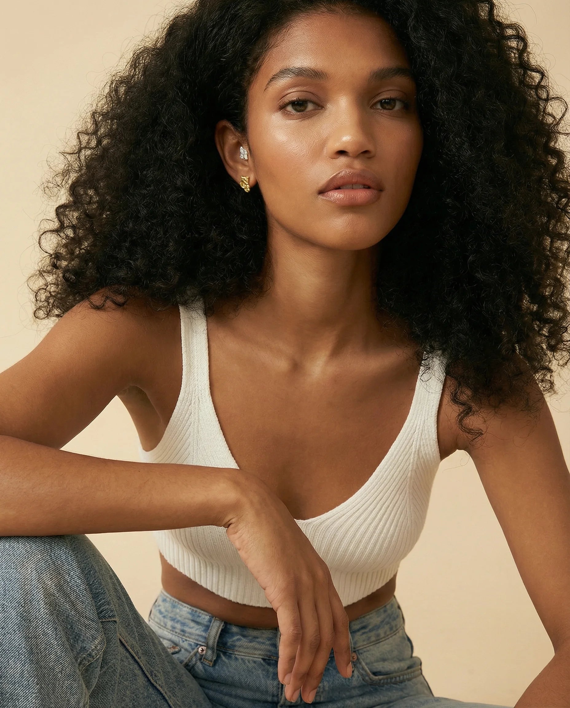 Model wearing both gold and silver earrings paired with a crop top and blue jeans. Effortless day-to-night styling with Frequency Paris-Ibiza organic hammered Grounding earrings.